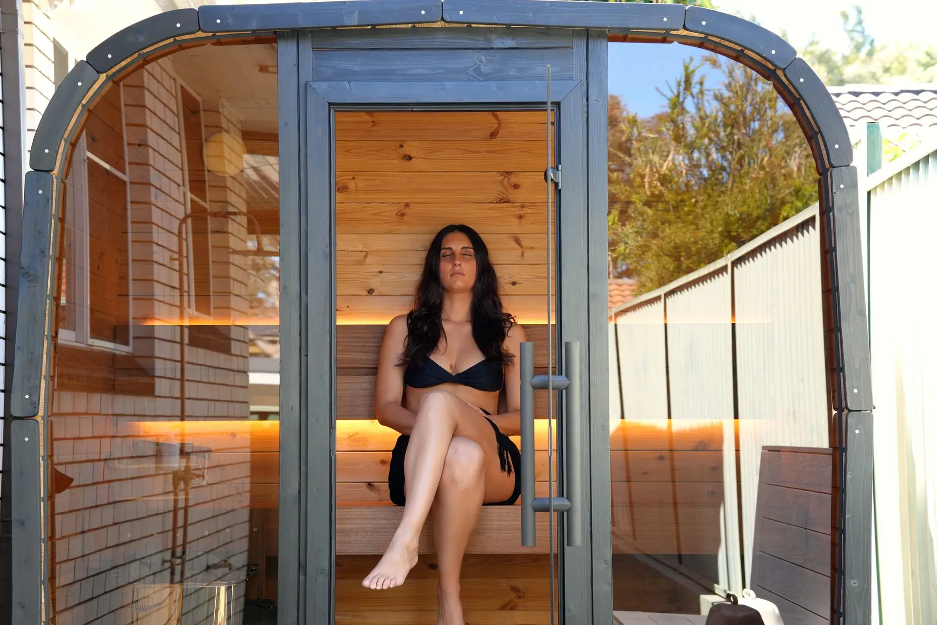 Mia seated inside the Koda, with the complete curved front and glass door in view