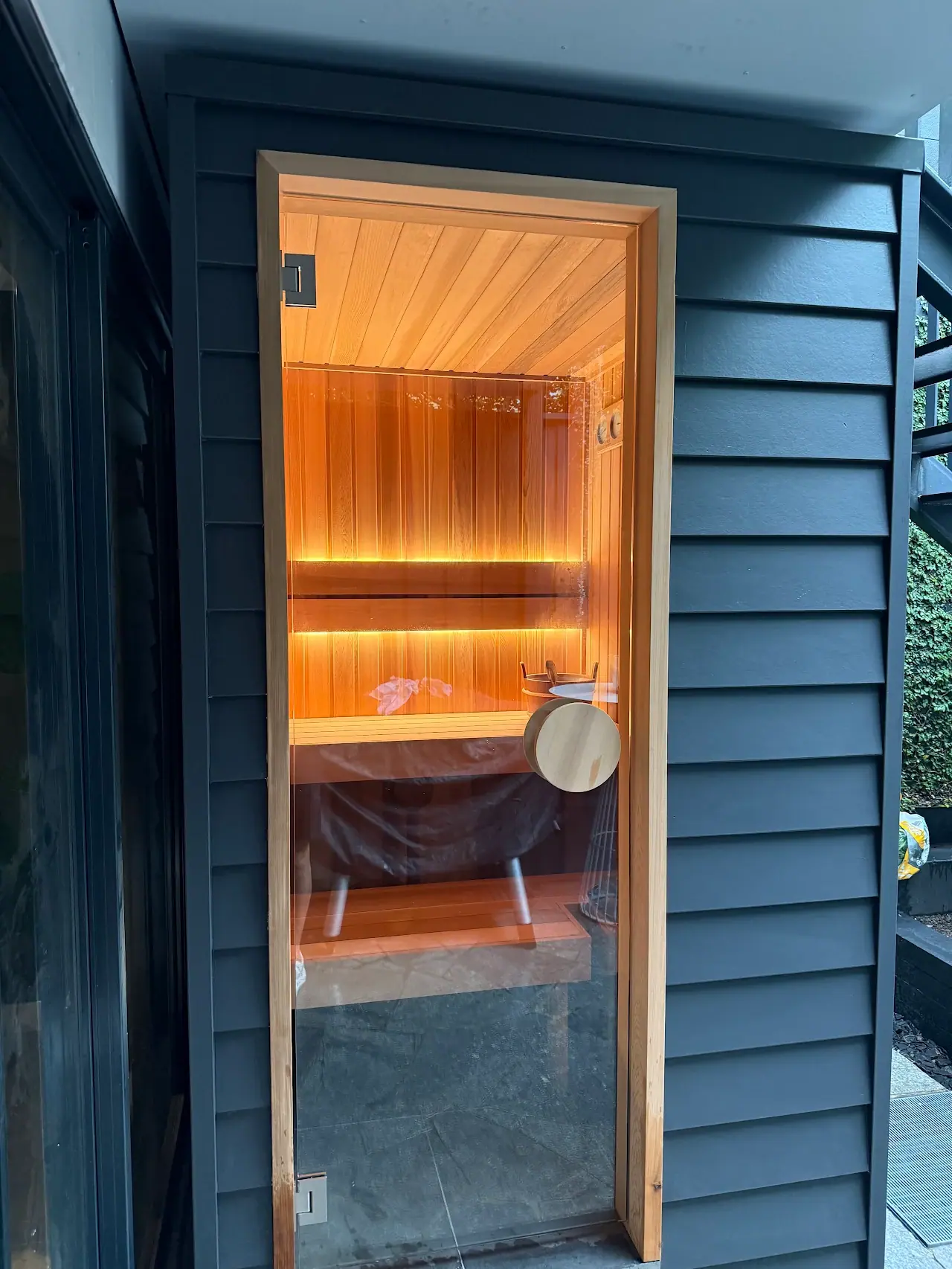 Completed custom sauna integrated into a Sydney home with full-height glass and illuminated cedar benches
