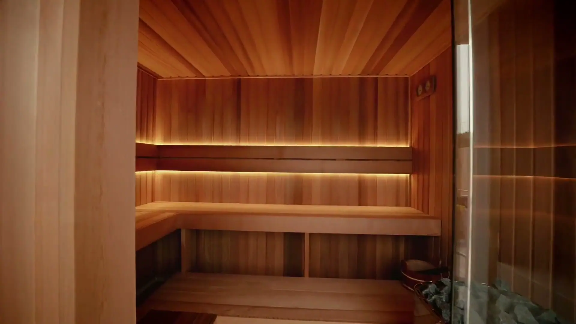 Completed custom sauna with tiered cedar benches and concealed lighting